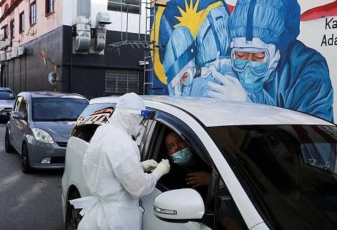 JALANI UJIAN COVID-19: Seorang pekerja kesihatan sedang melakukan ujian Covid-19 ke atas seorang pemandu di satu pusat ujian di Shah Alam, Selangor, sedang varian Omicron terus menular di Malaysia. - Foto REUTERS