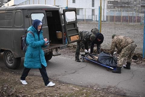 PETAKA PERANG: Seorang wanita berjalan melepasi dua askar Ukraine yang sedang mengangkat mayat warganya yang menjadi mangsa serangan tentera Russia di utara Kyiv, kelmarin. Presiden Ukraine, Encik Volodymyr Zelensky, berkata tentera Russia menyasarka