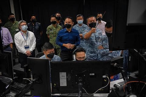 LIHAT CARA LATIHAN DISELARAS: Encik Zaqy Mohamad (berkemeja biru) dan Timbalan Komander ADTF, Kolonel Aldrin Tan (kiri Encik Zaqy), menyaksikan pasukan RSAF menjalankan Latihan Perisai Siap Siaga di Pusat Kawalan Trafik Udara Singapura semalam. - Fot