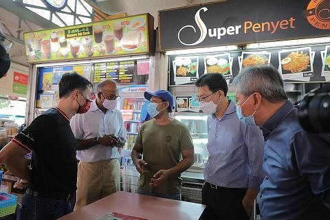 GALAK PENDAKAPAN DIGITAL: Encik Shanmugam (dua dari kiri) bertemu Encik Hamzah Mohamad (tengah), seorang tukang masak gerai Super Penyet yang terletak di Pasar dan Pusat Penjaja Chong Pang sambil diiringi (dari kiri) pengurus negara DBS untuk Singapu