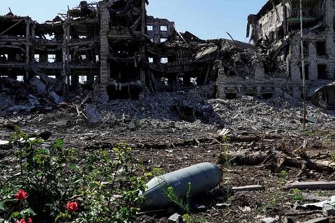 KESAN PERANG: Sebuah bom yang tidak meletup di hadapan bangunan yang musnah di Mariupol. - Foto AFP