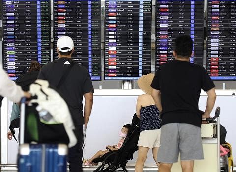 ELAKKAN RUANG UDARA: Penumpang melihat papan maklumat penerbangan di Lapangan Terbang Antarabangsa Suvarnabhumi di wilayah Samut Prakan, Thailand semalam. Thailand telah memberitahu tiga syarikat penerbangan negara itu supaya mengelakkan ruang udara 