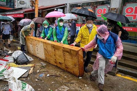 KERJA PEMBERSIHAN: Sekumpulan pekerja membersihkan longgokan sampah sarap di kawasan Pasar Namseong di daerah Gangnam kelmarin selepas hujan lebat terburuk melanda tempat itu.
