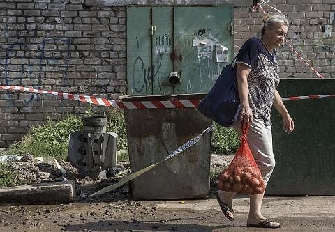 KESAN SERANGAN: Seorang wanita setempat jalan melintasi serpihan roket selepas serangan di bandar Mykolaiv, Ukraine. - Foto EPA-EFE