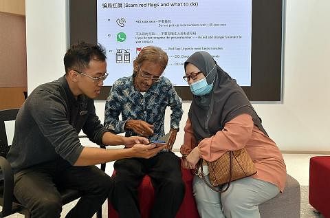 BELAJAR KENALI PENIPUAN: Pegawai bank Encik Robert Tan (kiri) bercakap dengan pelanggan Encik Zainal dan Cik Zohrah mengenai penipuan di cawangan bank OCBC di Tampines. - Foto ALPHONSUS CHERN