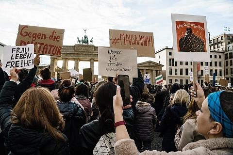 BANTAHAN MEREBAK: Penunjuk perasaan memegang plakad semasa perhimpunan membantah kematian Cik Mahsa Amini, di hadapan Gerbang Brandenburg di Berlin, Jerman, 28 September 2022. Cik Mahsa seorang wanita Iran berusia 22 tahun, telah ditangkap polis penc