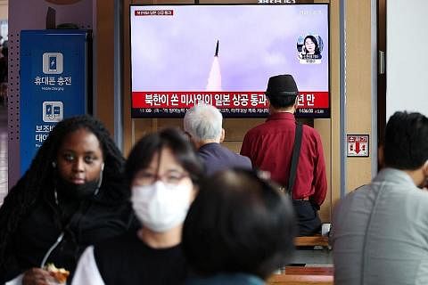 IKUTI BERITA: Orang ramai menyaksikan laporan berita di televisyen mengenai pelancaran peluru berpandu balistik terbaru Korea Utara yang melepasi Jepun. - Foto REUTERS