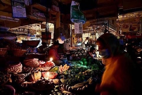 BERGELAP:(Kiri sekali) Peniaga di pasar Dhaka menjual sayur-sayuran terpaksa menggunakan lilin akibat krisis bekalan elektrik di Bangladesh. (Kiri) Orang ramai berjalan dalam keadaan gelap - Foto-foto AFP