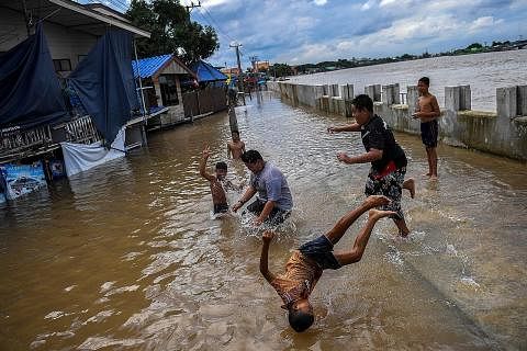 MAIN AIR: Sekumpulan kanak-kanak bermain di kawasan jalan raya yang banjir selepas hujan lebat berdekatan masjid Tha-it di wilayah Nonthaburi di luar Bangkok, Thailand, kelmarin.