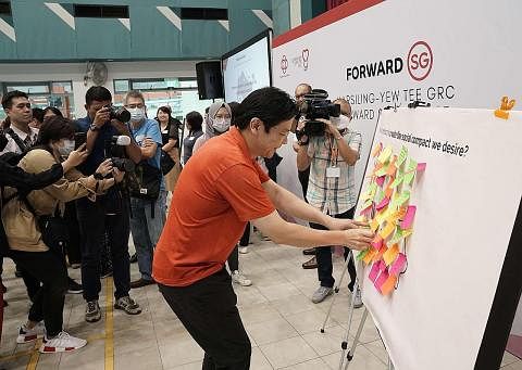SUARAKAN HALA TUJU: Encik Wong menampal nota 'post-it' di papan tanda yang mengajak para peserta menulis keinginan mereka untuk kompak sosial baru Singapura. - Foto GRC MARSILING-YEW TEE