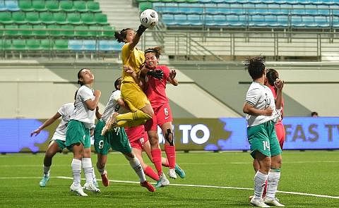 CUBA REBUT BOLA: Pemain Singapura, Nur Farhanah (jersi merah), melompat tinggi untuk cuba menanduk bola semasa menentang Indonesia kelmarin. - Foto BH oleh DESMOND WEE