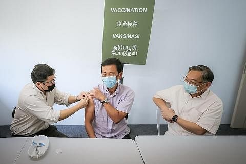 TERIMA VAKSIN BIVALEN: Encik Ong (tengah) menerima dos penggalak menggunakan vaksin bivalen Moderna/Spikevax di pusat ujian dan vaksinasi bersama (JTVC) Commonwealth semalam sambil disaksikan Encik Gan (kanan). - Foto BH oleh GAVIN FOO