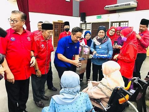 SANTUNI AHLI: Encik Isham Jalil (berbaju kemeja biru) menyampaikan cenderahati kepada warga emas (berkerusi roda) semasa menghadiri acara anjuran Umno dan Barisan Nasional pada Ogos lalu. - Foto ihsan ISHAM JALIL