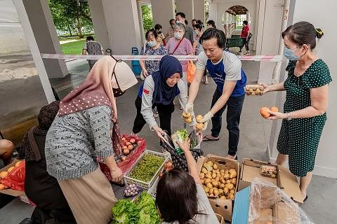SAYUR UNTUK SEMUA: Cik Azlina Ahmad bertudung biru), dan suaminya, Encik Nurfahmi Sazali, membahagi-bahagikan sayur-sayuran yang masih elok yang 'diselamatkan' dari pasar borong Pasir Panjang kepada mereka yang memerlukan.