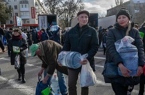 DIHULUR BEKALAN AIR MINUMAN: Penduduk di bandar Kherson, Ukraine, membawa air pulang semasa pengagihan bekalan bantuan baru-baru ini. - Foto AFP