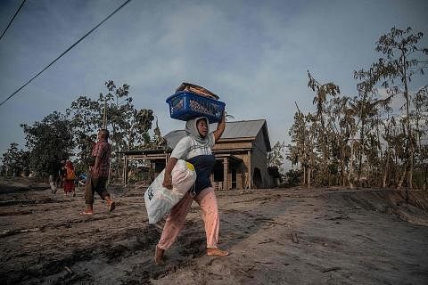 BERGEGAS LARI: Seorang wanita menyelamatkan barangannya berikutan letusan Gunung Semeru di kampung Kajar Kuning di Lumajang, Indonesia semalam. - Foto AFP
