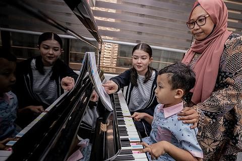 TEKUN BERLATIH: Naseer Gampang Puruhita (atas) yang mempunyai autisme berlatih dengan bimbingan guru piano, Cik Georgina Scott, dan disaksikan ibunya, Cik Ayu Suparman (kanan). - Foto BH oleh NUR DIYANA TAHA