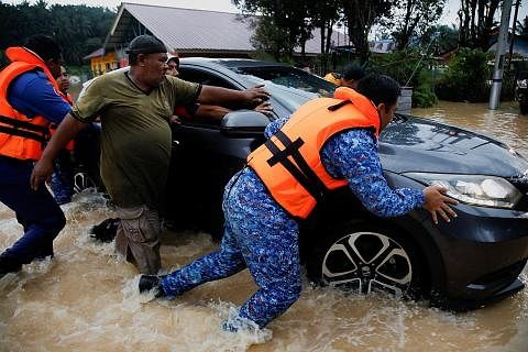 BANTU PEMANDU TERPERANGKAP DALAM BANJIR: Beberapa orang dilihat membantu menolak sebuah kereta yang terperangkap dalam banjir kilat yang melanda kawasan Klang di Selangor pada hujung minggu lalu. - Foto REUTERS