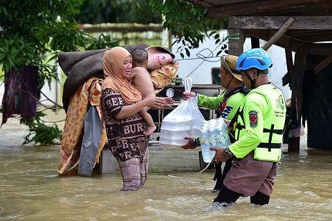 BANTU PENDUDUK: Pekerja agensi bencana mengagihkan makanan dan air minuman kepada mangsa banjir di daerah Sungai Kolok di wilayah Narathiwat, Thailand. - Foto AFP