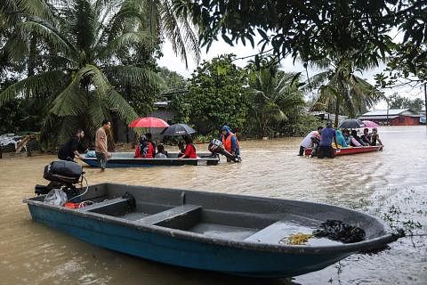 MASIH BERISIKO: Penduduk Kuala Terengganu dilihat menggunakan bot untuk mengharungi banjir di kawasan kediaman mereka. - Foto EPA-EFE