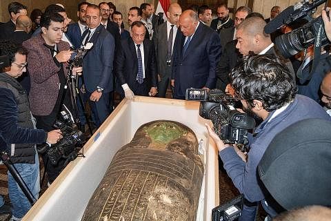 KHAZANAH PURBA DIKEMBALIKAN: Menteri Luar Mesir, Encik Sameh Shoukry (tengah, kanan) dan ketua Majlis Tertinggi Antikuiti, Encik Mostafa Waziri (tengah, kiri) dikelilingi oleh wartawan ketika mereka memeriksa sarkofagus kayu Mesir purba yang diserahk