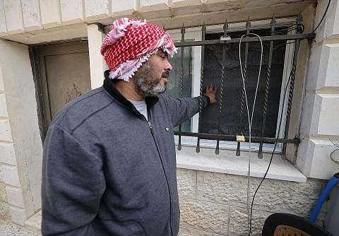 DIKEPUNG: Pakcik Khayri Alqam, lelaki yang membunuh tujuh orang di sebuah rumah ibadah Yahudi, memeriksa kepungan yang dibuat tentera Israel di kediaman keluarga Alqam di timur Baitulmakdis. - Foto AFP