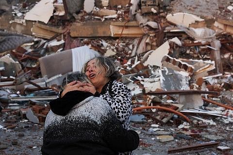 MANGSA GEMPA TERSELAMAT: Dua wanita ini berpelukan di hadapan serpihan runtuhan bangunan menyusuli gempa bumi kuat yang melanda bandar Hatay, Turkey, kelmarin. - Foto REUTERS