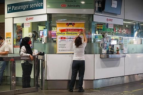 NOTIS PERJALANAN LEWAT: Kakitangan SMRT di Stesen MRT Admiralty memasang notis kelewatan perjalanan MRT. - Foto ST
