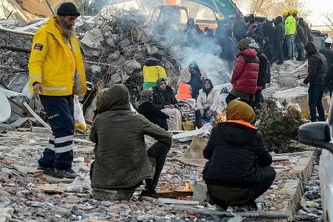 CABARAN GETIR: Saudara-mara mangsa duduk mengelilingi unggun api bersebelahan runtuhan di Adiyaman, Turkey, bagi mendapatkan kehangatan di tengah-tengah musim salji yang melanda negara itu ketika ini. - Foto AFP