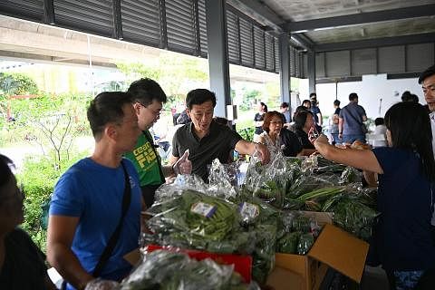 HIDUP LEBIH SIHAT: Encik Ong (tengah, berbaju hitam) bersama relawan mengagihkan sayur-sayuran kepada penduduk yang memerlukan di Pasir Ris Central. - Foto ST