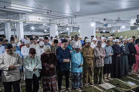 KEMBALI DIADAKAN: Para penduduk di kawasan Tampines mendirikan solat tarawih di kolong Blok 450 Tampines Street 42 pada Rabu malam sambil menyambut ketibaan bulan Ramadan. - Foto BH oleh SHAFIQ APANDI