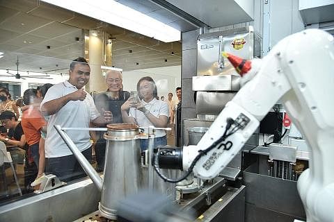 BARISTA ROBOT: Encik Sharael Taha (kiri) tertarik melihat barista robot membuat teh di sebuah gerai air di Pusat Penjaja One Punggol yang dirasmikan pada Sabtu. - Foto BH oleh M. O. SALLEH