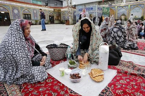 JUADAH IFTAR: Seorang relawan dari Yaman menyediakan juadah buka puasa di ibu kota Sanaa pada Isnin. - Foto-foto AFP BERKUMPUL: Keluarga di Iran ini berkumpul untuk membuka puasa pada Isnin di Emamzadeh Saleh di Teheran, Iran.