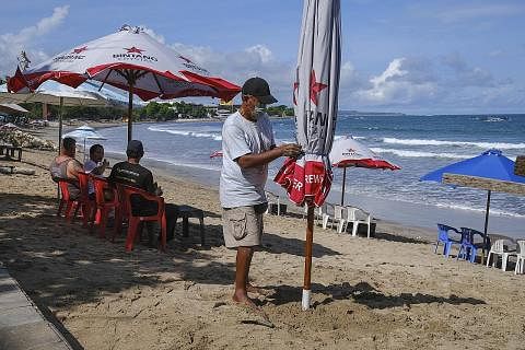 TARIKAN BALI: Seorang lelaki memasang payung di pantai di Kuta, Bali. Jumlah pelancong dalam negara yang berkunjung ke pulau pelancongan itu dijangka meningkat 20 peratus setiap hari semasa Hari Raya. - Foto EPA-EFE
