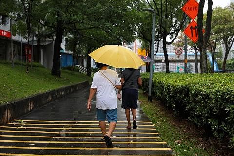 HUJAN: Kelihatan dua wanita berpayung dalam hujan di Pasir Ris Drive 6 pada 16 Mei 2023, selepas seminggu cuaca panas. - Foto ST