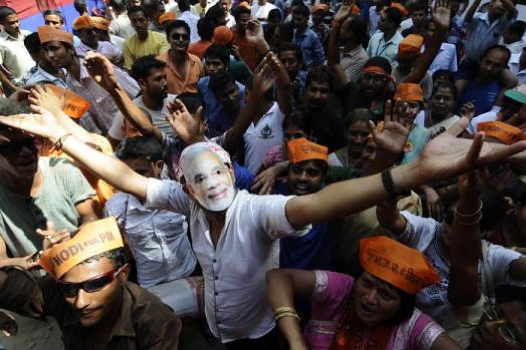 SAMBUT KEMENANGAN: Seorang pekerja BJP memakai topeng imej pemimpinnya yang bakal menjadi Perdana Menteri India baru, Encik Narendra Modi, ketika meraikan kemenangan parti itu dalam pilihan raya umum yang lalu. - Foto-foto AFP