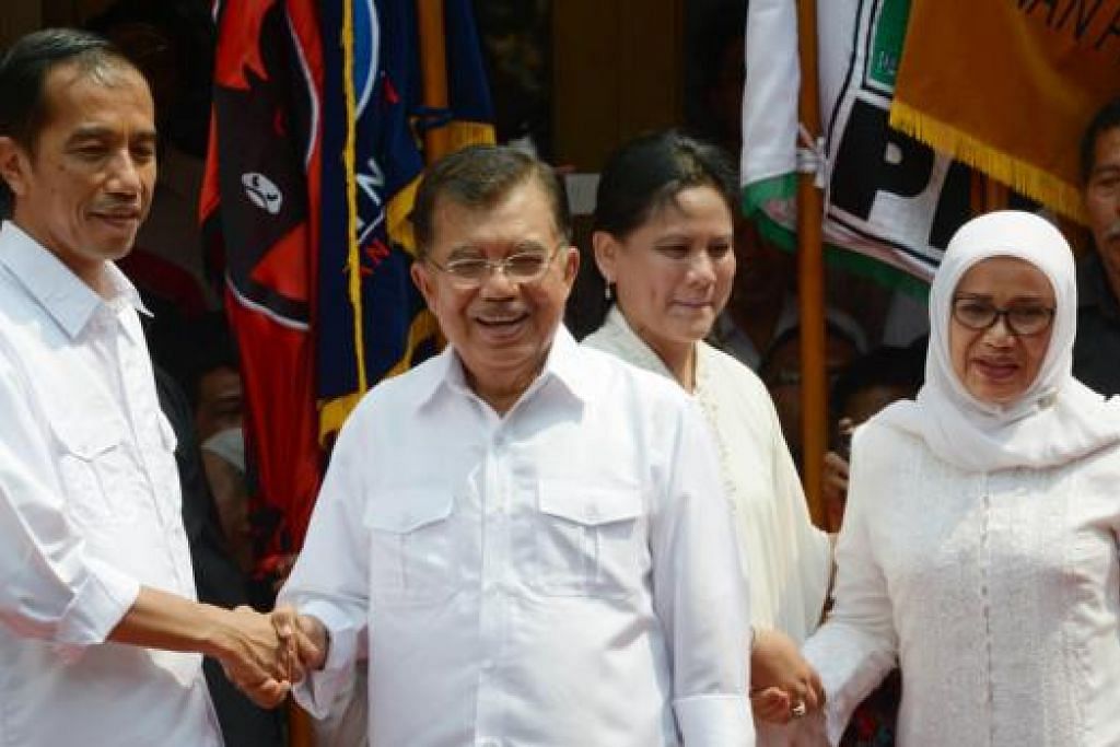SUDAH RASMI: (Dari kiri) Encik Joko Widodo yang lebih dikenali sebagai Jokowi berjabat tangan dengan calon Naib Presidennya, Encik Jusuf Kalla, sementara isteri Encik Widodo, Cik Iriana berjabat tangan dengan isteri Encik Kalla, Cik Mufidah, semasa mengumumkan pencalonan masing-masing di Jakarta semalam. - Foto AFP