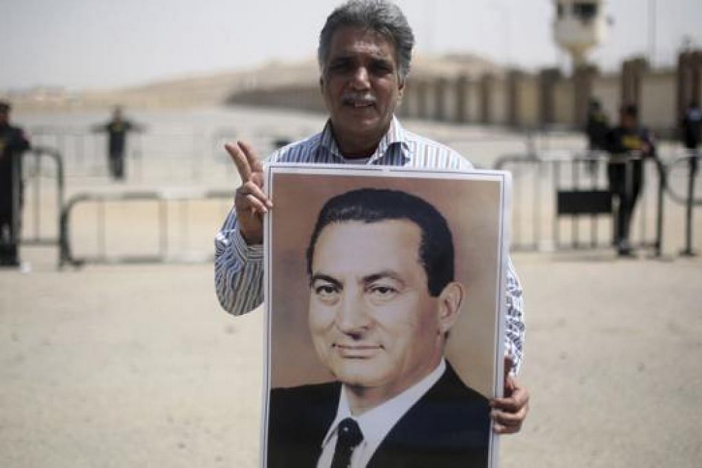 KEPIMPINAN SILAM: Penyokong memegang gambar mantan presiden Mesir, Encik Hosni Mubarak. Encik Hosni dihukum penjara tiga tahun semalam. - Foto REUTERS