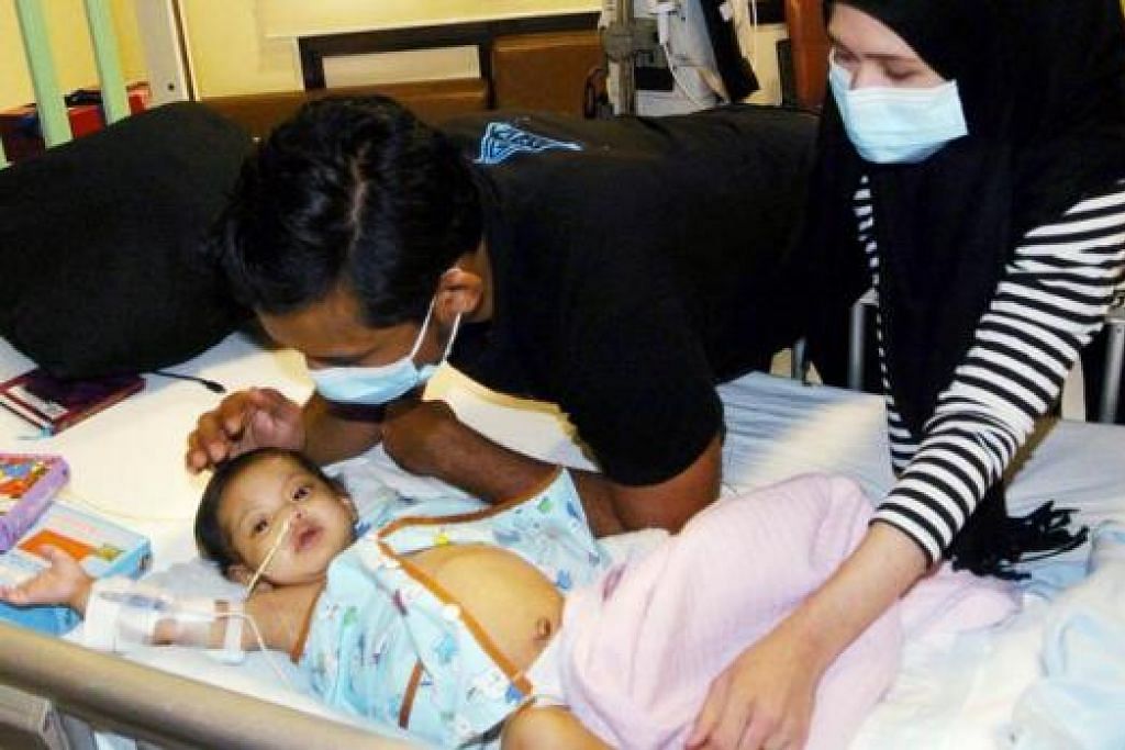 INGIN ANAK SEMBUH: Adra didampingi ibu bapanya kEncik Adzriefaiz dan Cik Suliza di wardnya di NUH. Adra sedang menanti untuk menjalani pemindahan hati yang dianggar menelan belanja $150,000. - Foto JOHARI RAHMAT