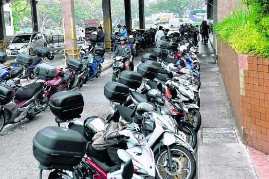 SESAK HANYA EMPAT JAM: Pekerja Malaysia singgah di kawasan sekitar Woodlands Point dengan meletakkan motosikal sehingga menyekat laluan sebatang lorong kereta di situ. - Foto JOHARI RAHMAT