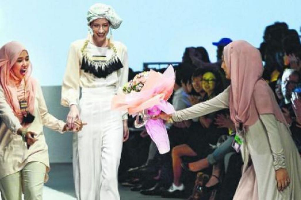 RIANG DIHARGAI: Cik Nur Hafizah Ghazali (kiri) saat diberikan sejambak bunga oleh pakar hias rambutnya, Cik Nurhanis Mohd Rohayat, di Festival Fesyen Audi Tent@Orchard di Ngee Ann City minggu lalu. - Foto ZAINAL YAHYA