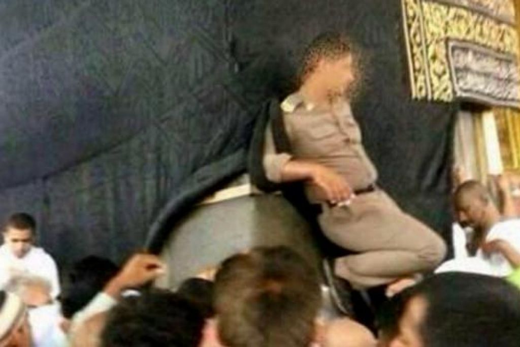 GAMBAR TERSEBAR DI INTERNET: Tindakan seorang anggota polis yang meletakkan kakinya pada Kaabah dikecam. - Foto GULF NEWS