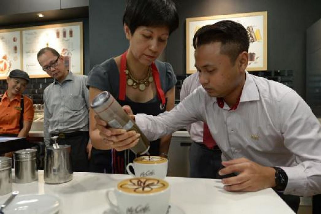 KEMAHIRAN MEMBUAT KOPI: Jurulatih McCafe, Encik Mohamed Hilmi, menunjukkan Menteri Cik Indranee Rajah cara membuat kopi latte di Akademi Latihan McCafe di ITE Kolej Barat. - Foto THE STRAITS TIMES