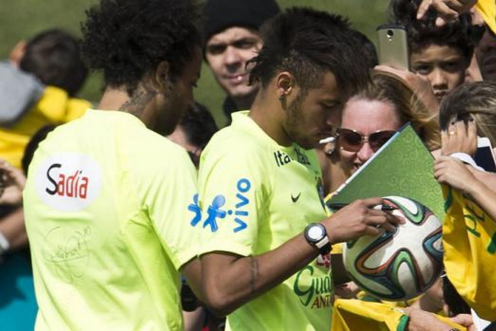LAYAN PEMINAT: Bintang Brazil, Neymar (kanan), dan Marcelo sibuk menandatangani autograf dan memikul cabaran berat memenangi Piala Dunia untuk rekod kali keenam bagi menenteramkan sesetengah warga yang tidak puas hati terhadap kos menggunung menganjurkan temasya bola sepak itu. - Foto AFP