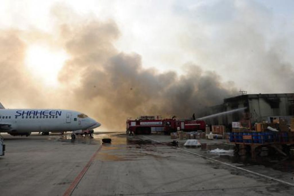TERBAKAR: Bomba Pakistan memadamkan kebakaran di sebuah bangunan di Lapangan Terbang Antarabangsa Jinnah di Karachi kelmarin selepas ia diserang sekumpulan militan Taleban. - Foto-foto AFP