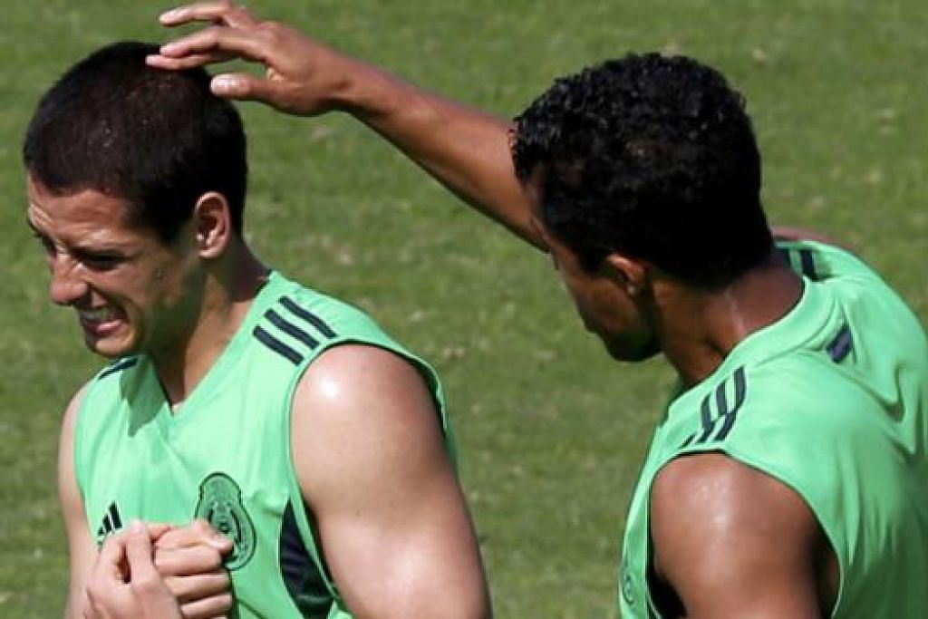 HILANGKAN STRES: Dua pemain Mexico, Giovani dos Santos (kanan), sempat menyakat rakannya Javier 'Chicharito' Hernandez, semasa persiapan menjelang pertemuan dengan Cameroon. – Foto REUTERS