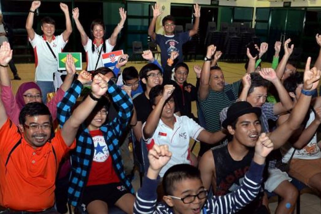 TURUN PADANG: Encik Zainal (kiri) bersama isteri dan lima anak lelakinya menyertai penduduk untuk menyaksikan siaran langsung perlawanan pembukaan Piala Dunia di Kelab Masyarakat Pasir Ris East. – Foto-foto TAUFIK A. KADER