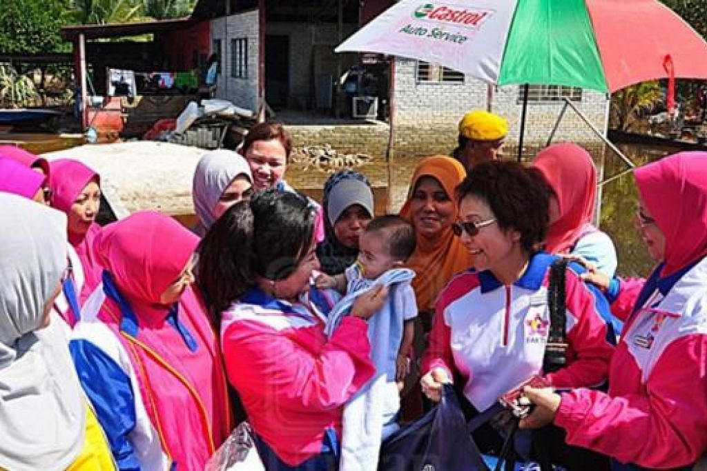 SAMA SIMPATI: Datin Rosmah mendukung bayi penduduk tempatan ketika melakukan misi bantuan pasca banjir di Projek Perumahan Rakyat Termiskin (PPRT) Rimba Raja, Lambor Kanan, Pasir Salak, Perak. - Foto MINGGUAN MALAYSIA