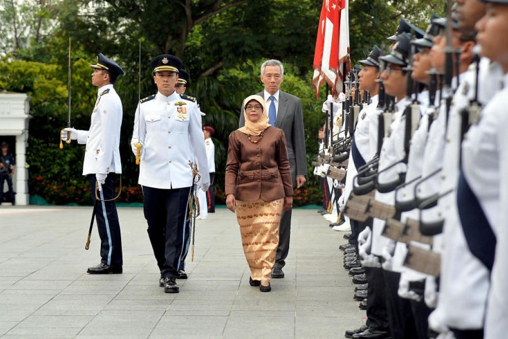 TINJAUAN PERTAMA: Puan Halimah meninjau kontinjen kawalan kehormatan, dengan diiringi Perdana Menteri Lee Hsien Loong. 