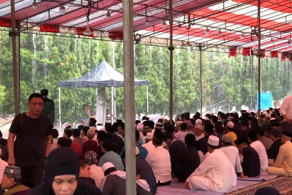 Muslims perform Eid prayers while keeping dry under tentage built by Shen Fu Gong Temple despite heavy rain